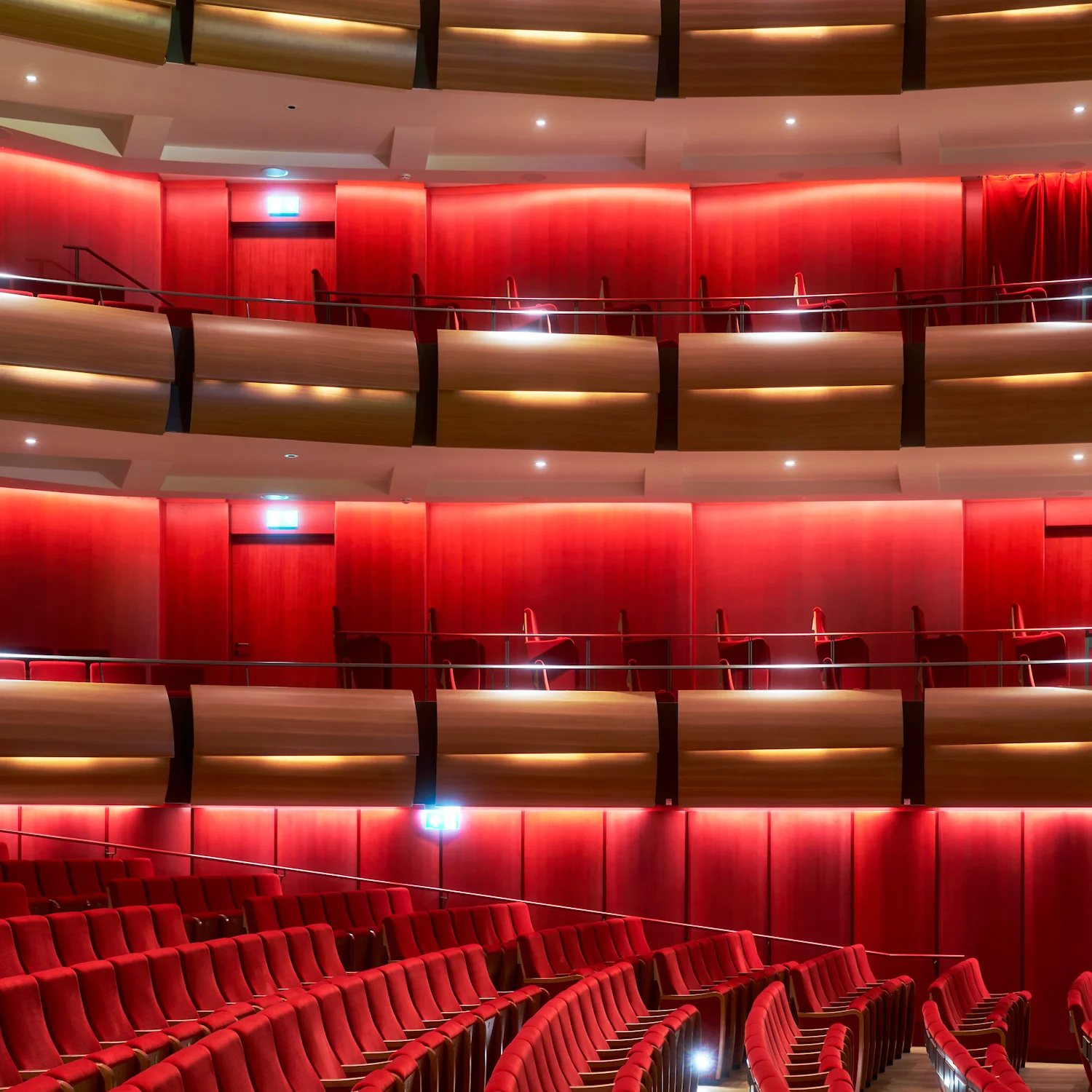 Large theatre auditorium featuring tiered seating upholstered in red Kvadrat fabric