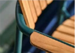 Side view of Mindo 119 chair showing teak armrest flowing into the slim painted aluminium frame and comfortable contoured seat.