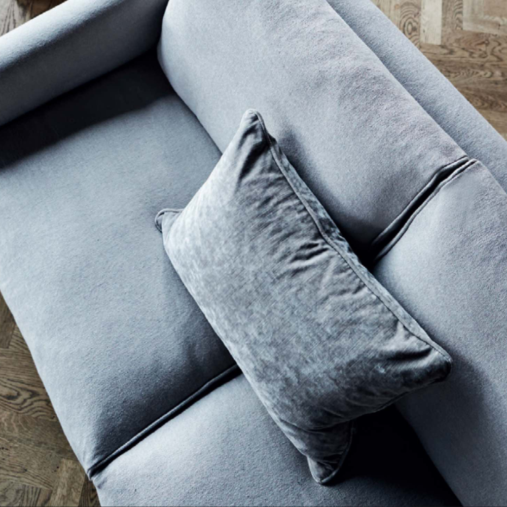 Detail of the Eilersen Streamline Sofa in light grey fabric, showing the seat cushion and back pillow on herringbone flooring.