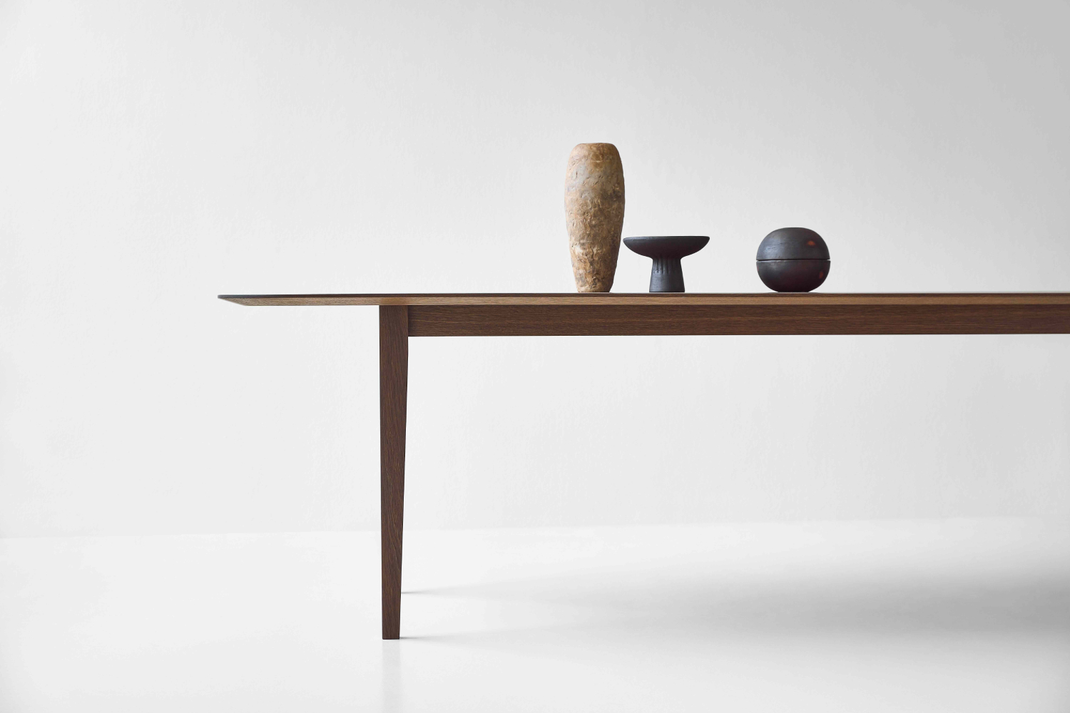 Close-up of the DK3 Kias Table in smoked oak, highlighting the sculpted corner joinery.