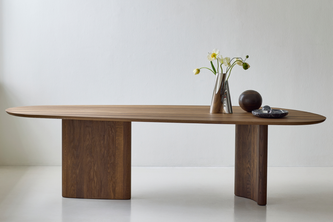 Minimal side profile of the DK3 Tangent Table in smoked oak, with simple sculptural décor placed along the tabletop.